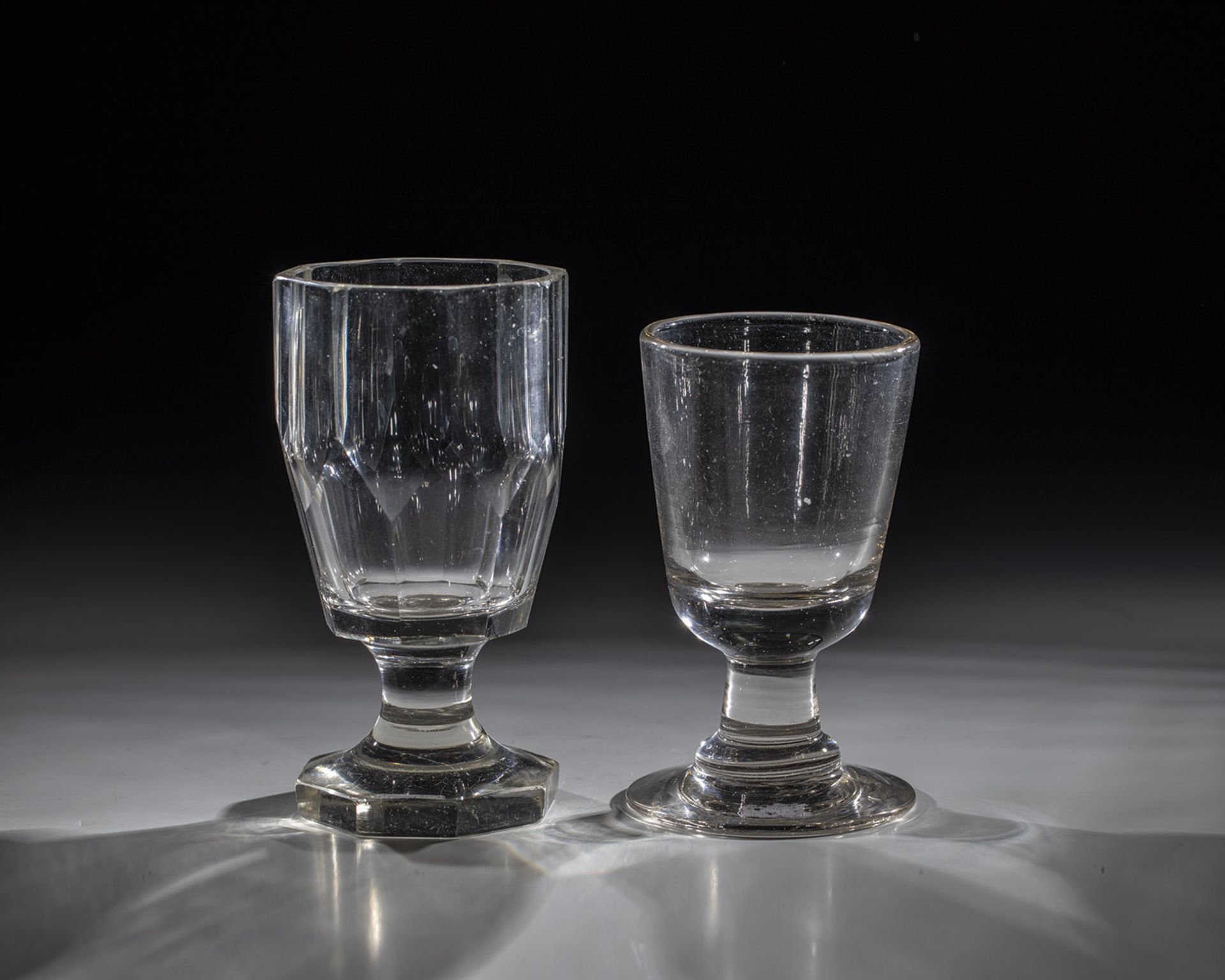 Two foot cups, 19th century, colourless glass. A beaker faceted cut. H. 12.4-14.2 cm