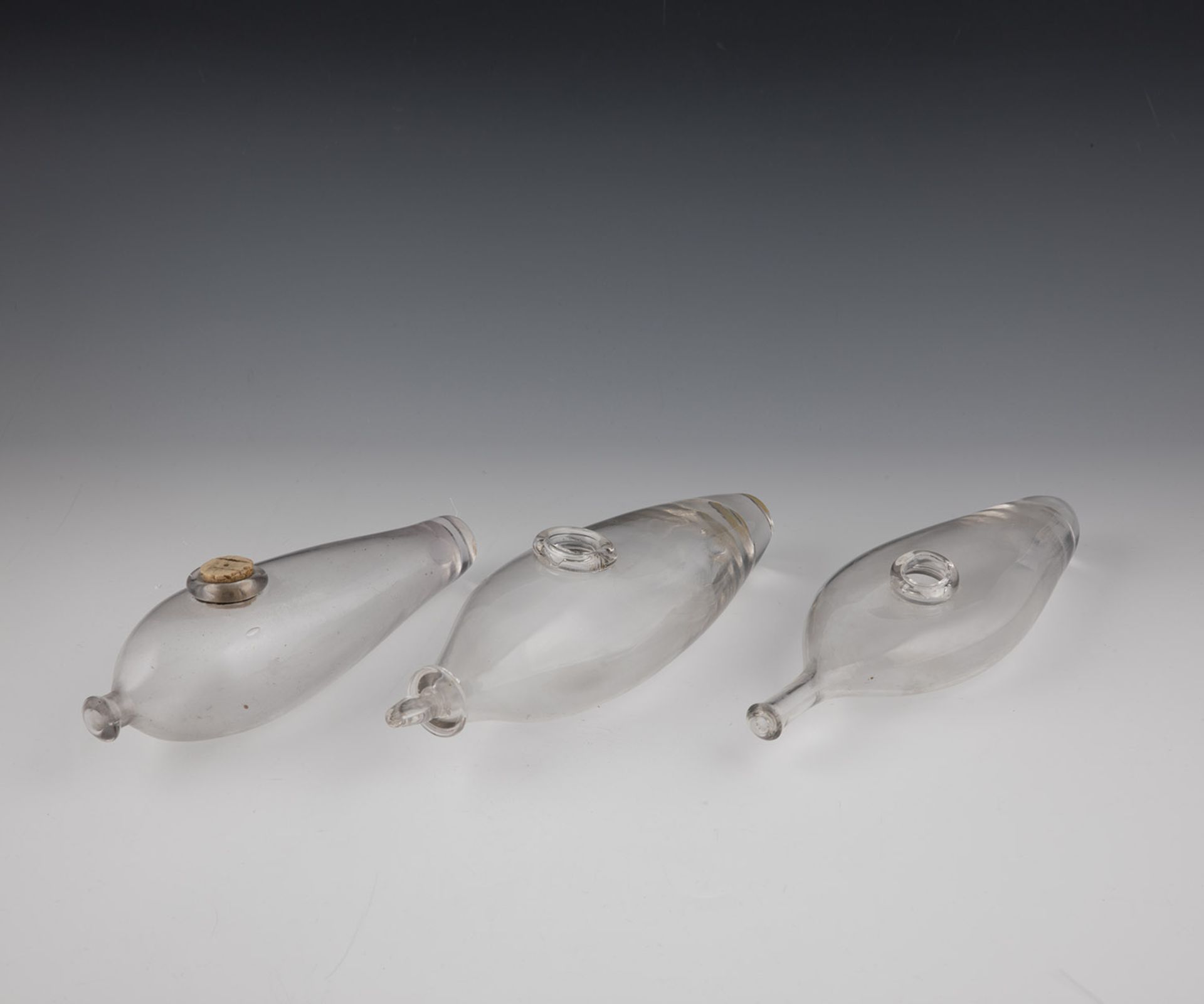 Three feeding bottles France, 19th century Grey-tinted glass. H. 20.5 to 23 cm.