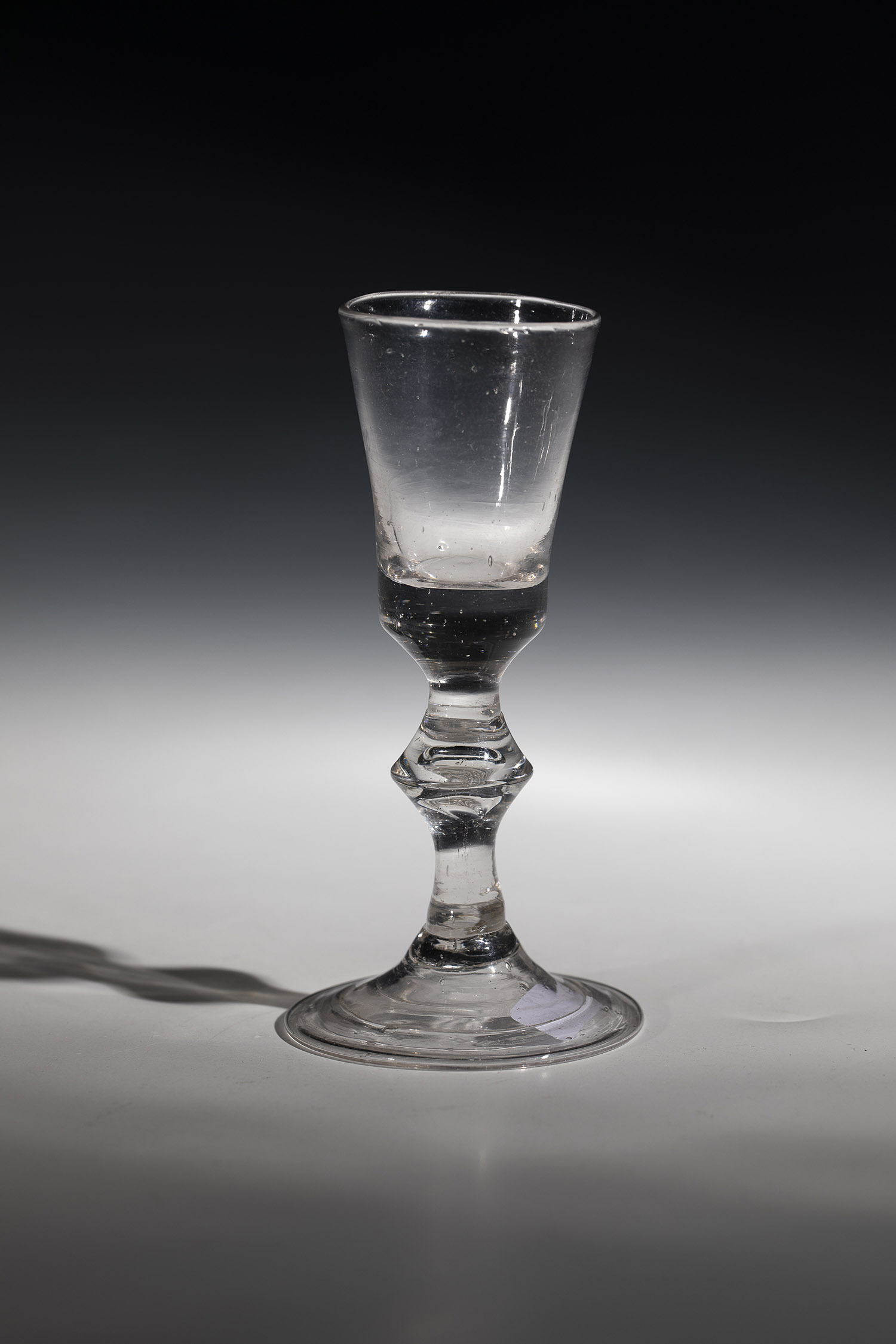 Shot glass, 18th century, disc base with downward turned-edge. Baluster shaft with punctured air