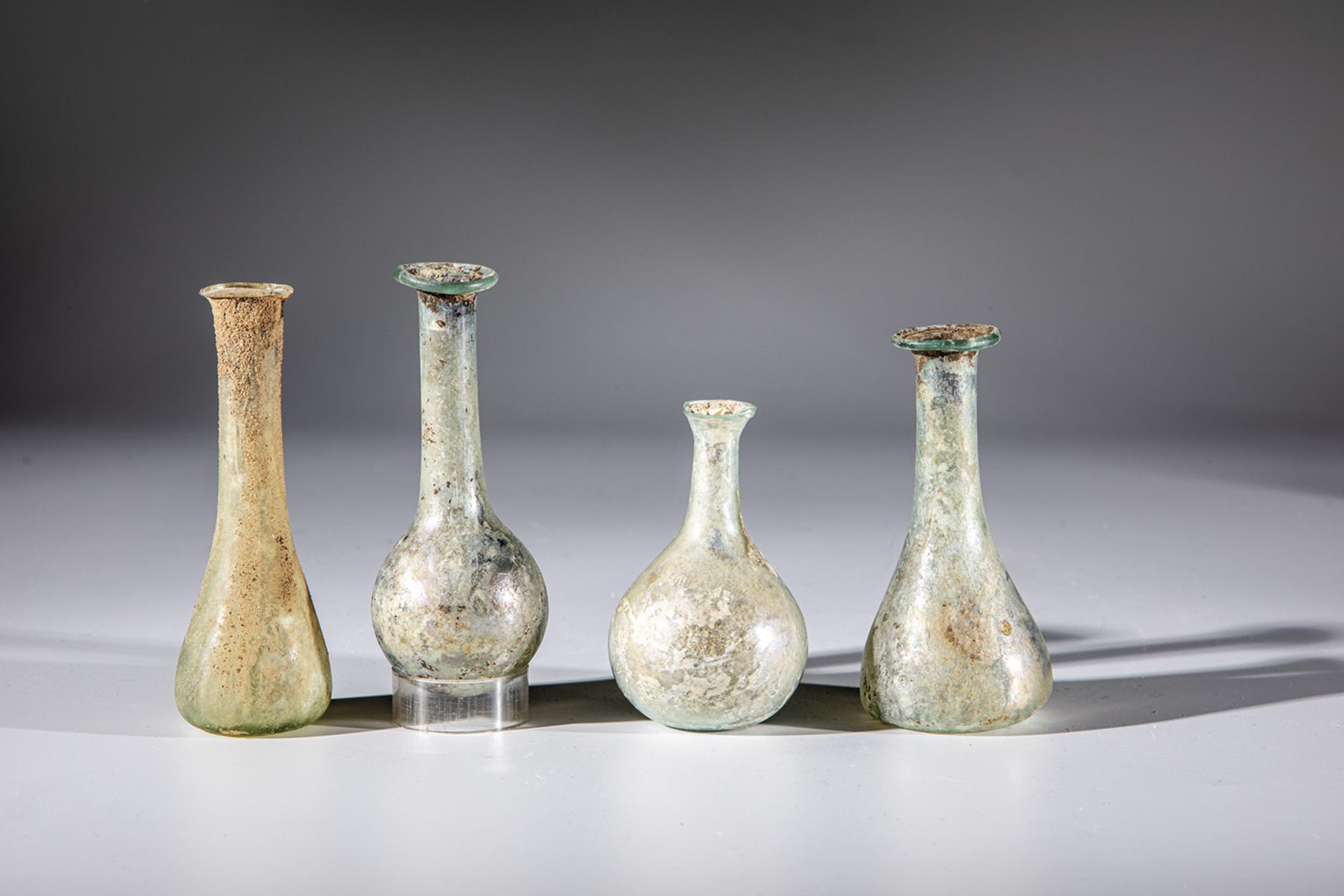 Four long-necked bottles Eastern Mediterranean, 1st-4th century AD. Greenish glass. One vial