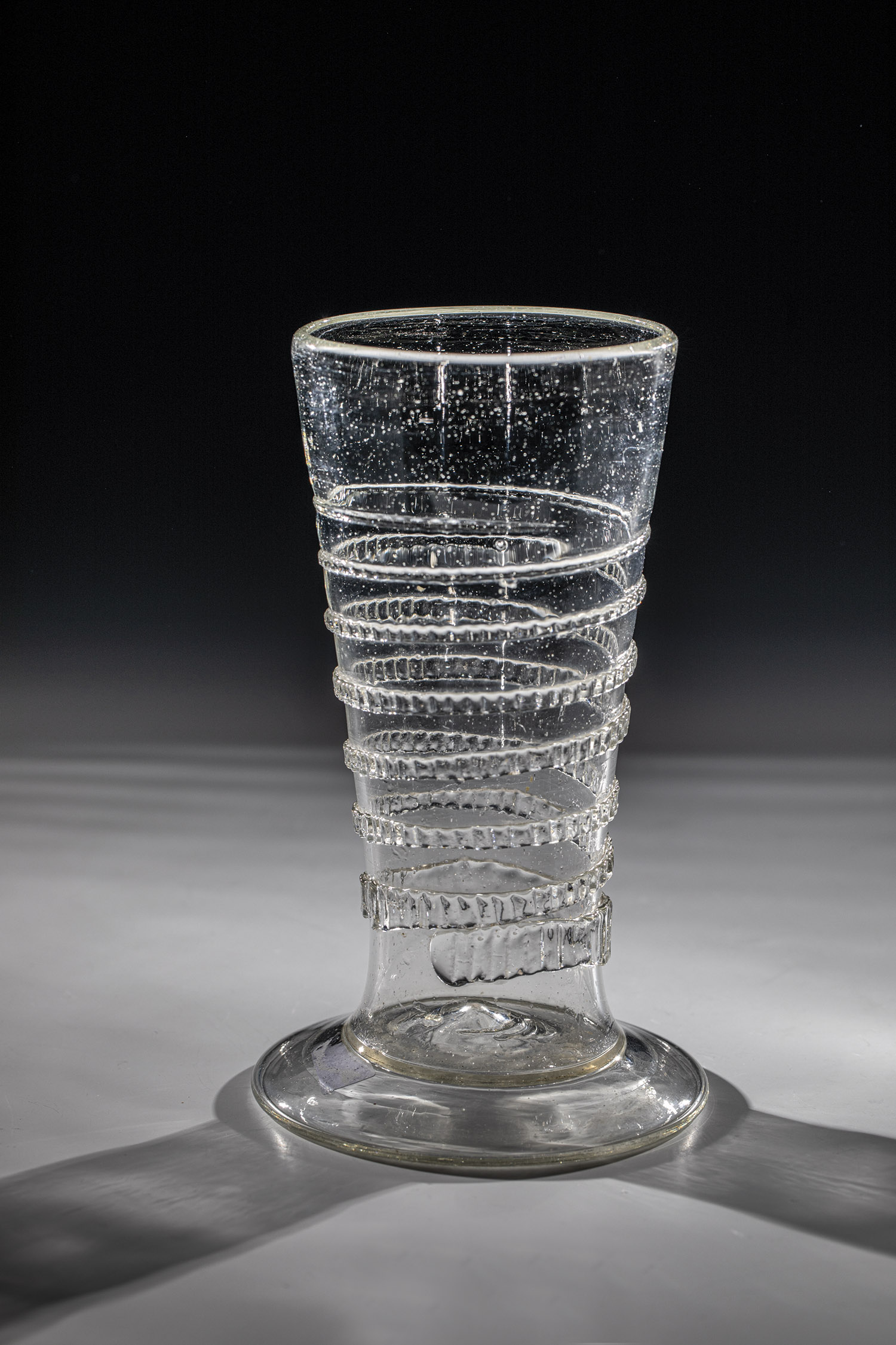 Tapeworm glass German 17th century Grey-tinted glass with flared, compressed stand, high-pitched