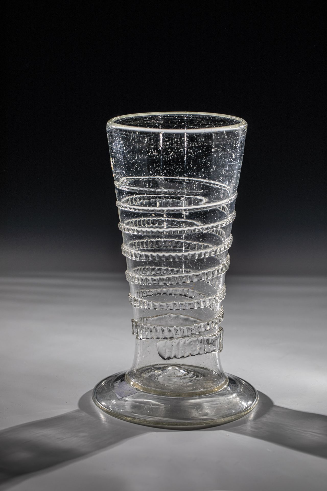 Tapeworm glass German 17th century Grey-tinted glass with flared, compressed stand, high-pitched