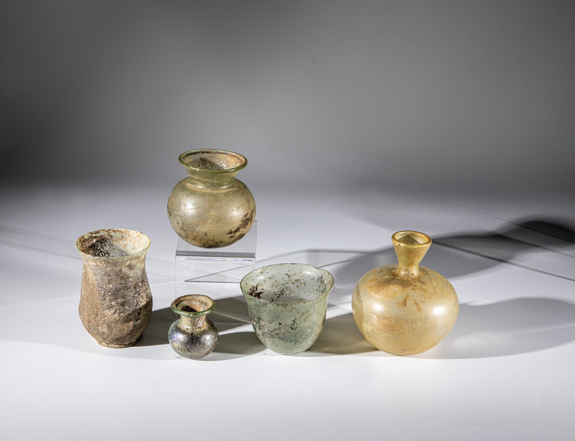 Two cups and three bottles Middle Eastern, 2nd-4th century AD. Colourless or greenish glass.