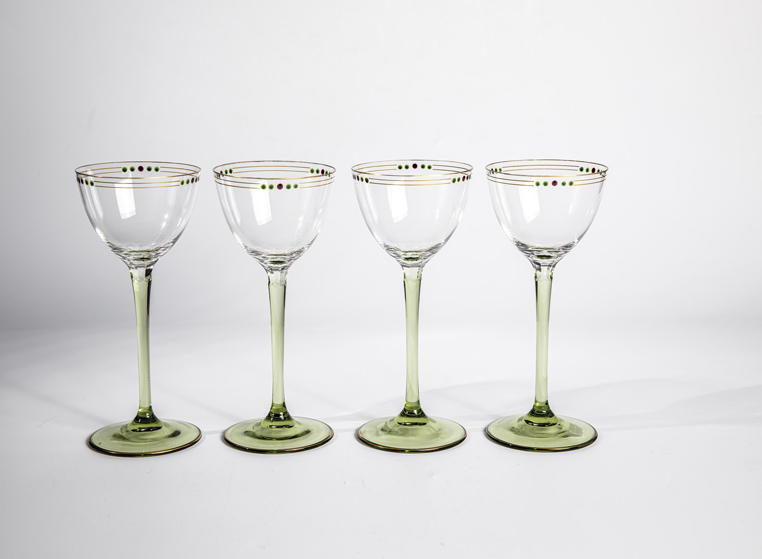 Four drinking glasses of Bohemia, circa 1910 feet and stems in green glass. Peel grind at the base