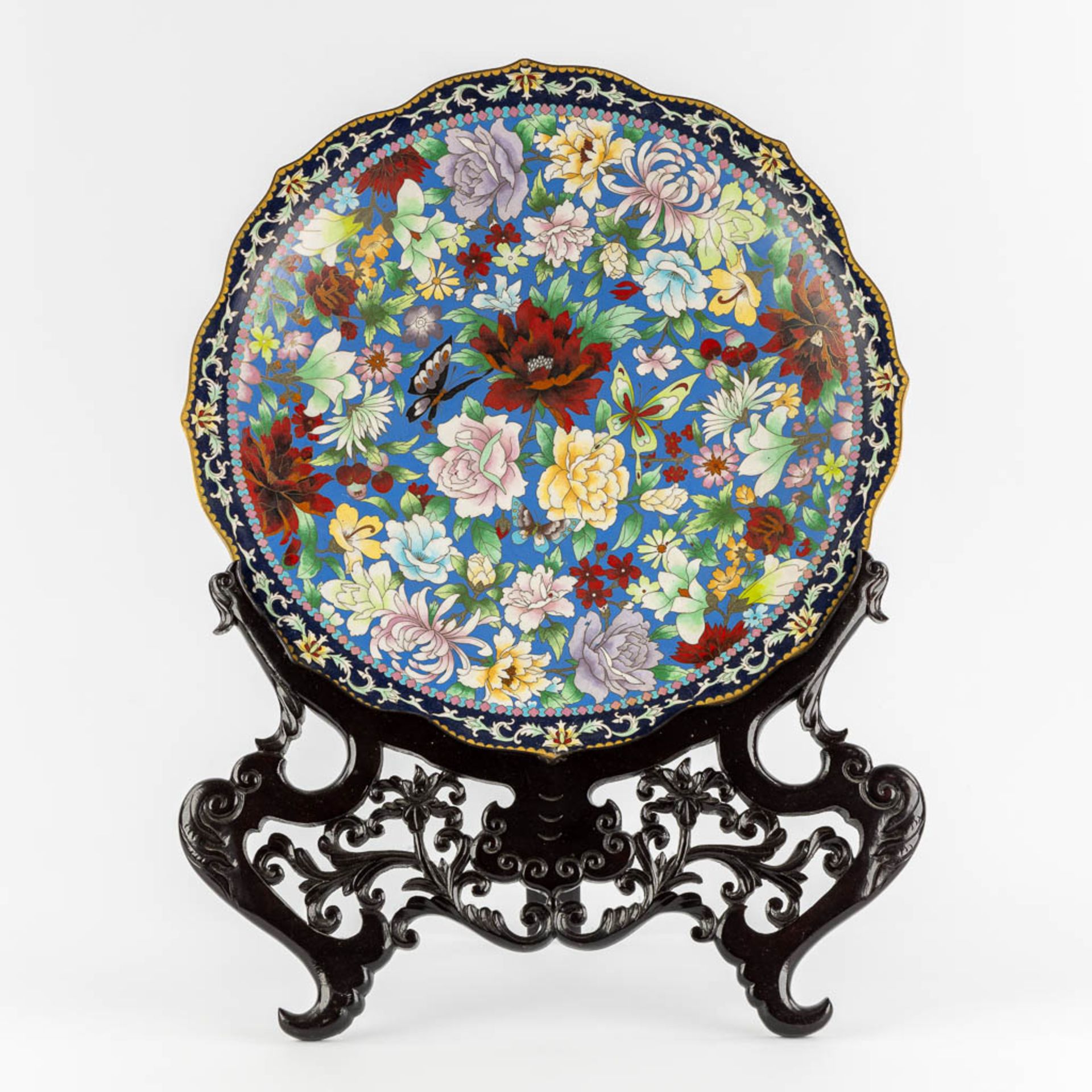 A large Chinese Cloisonné plate in an openworked sculptured wood stand. (W:51 x H:67 cm)