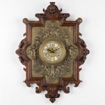 A wall-mounted clock, sculptured oak and repousse copper, decorated with putti and angels. 19th C. (