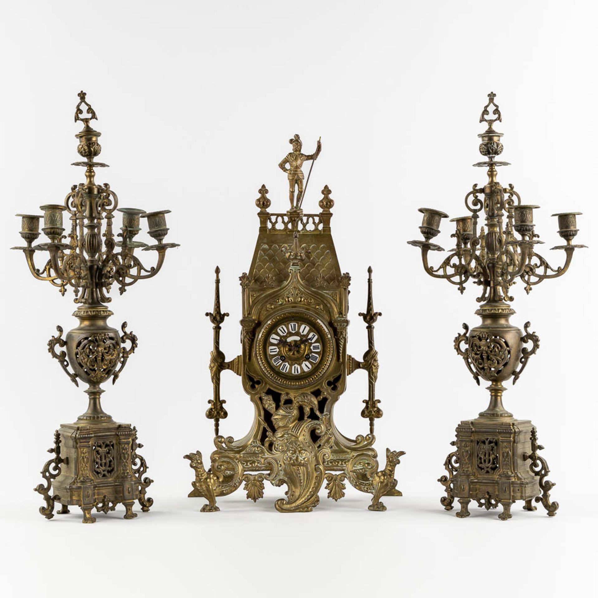 A three-piece mantle garniture in the shape of a castle with a knight, patinated bronze. Circa 1900.