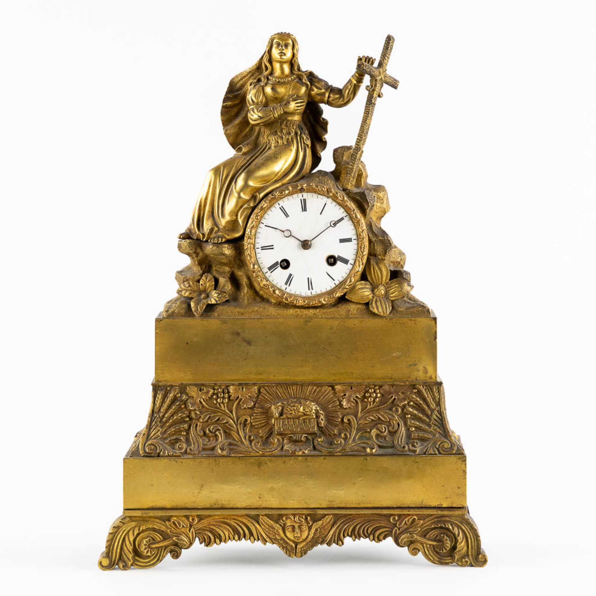 A mantle clock with a religious scène, gilt bronze in a Louis Philippe style. 19th C. (L:10 x W:30 x