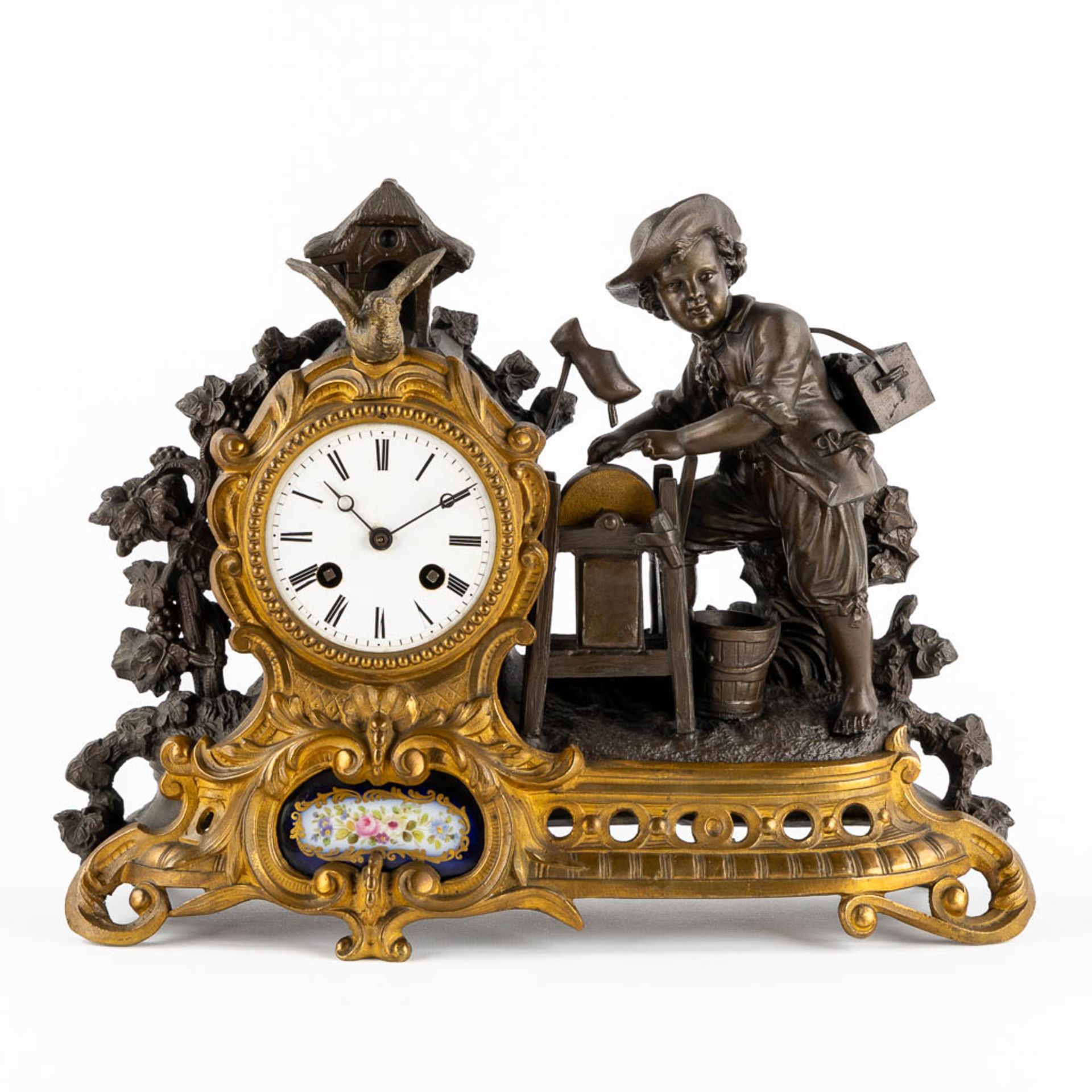 A mantle clock, patinated and bronze and spelter, image of a Wooden shoemaker. 19th C. (L:12 x W:36
