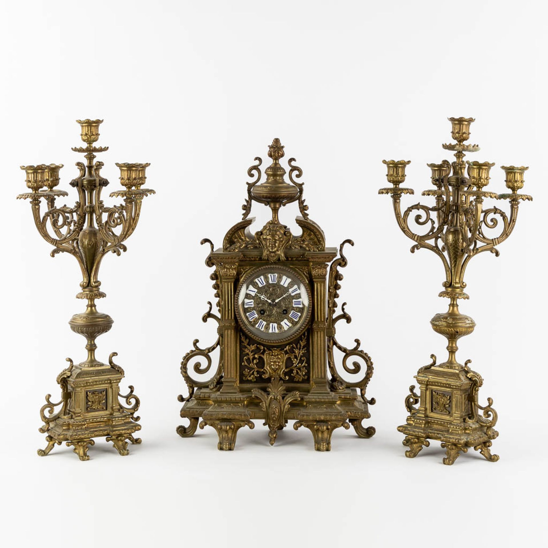 A three-piece mantle garniture clock and candelabra, patinated bronze. (L:16 x W:33 x H:50 cm)