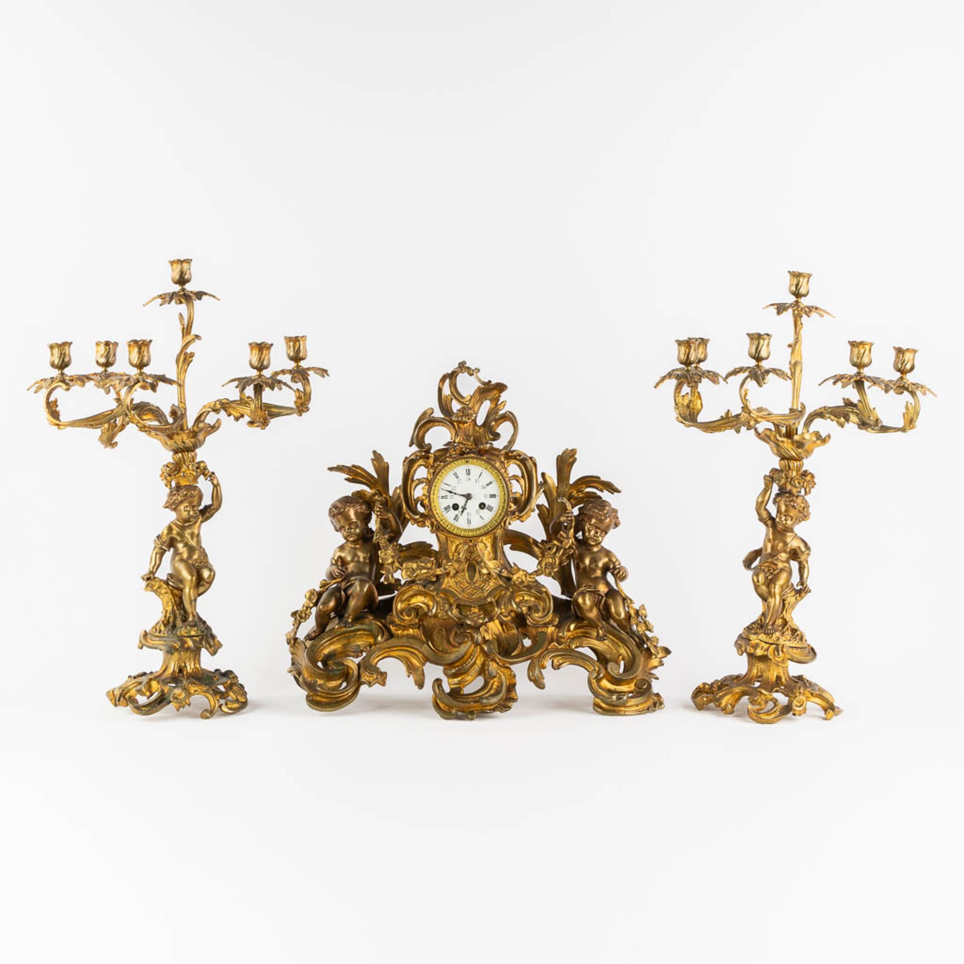 A three-piece mantle garniture clock and candelabra, gilt bronze. 19th C. (L:21 x W:55 x H:48 cm)