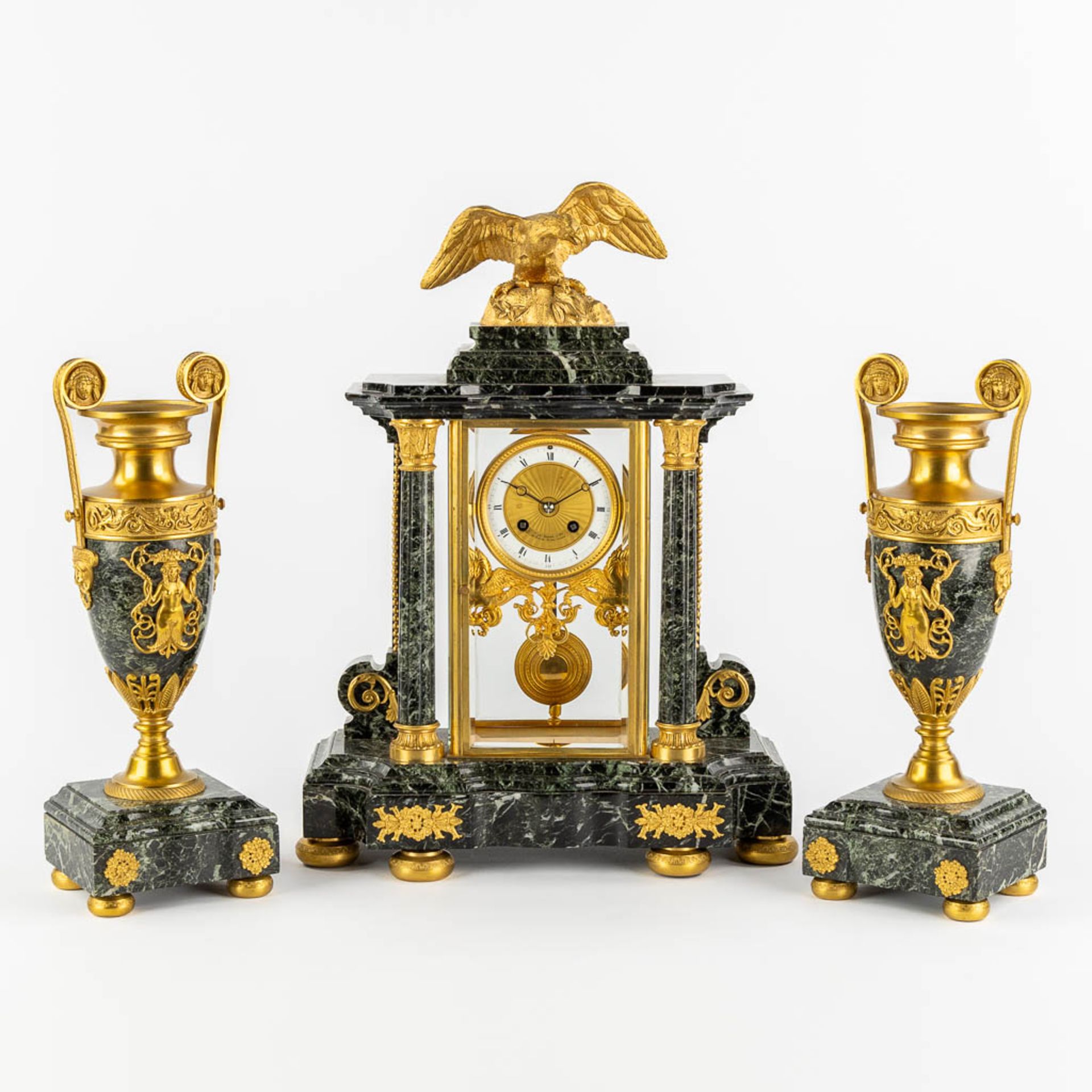 A three-piece mantle garniture clock and urns, gilt bronze on green marble, Empire style. France, 19