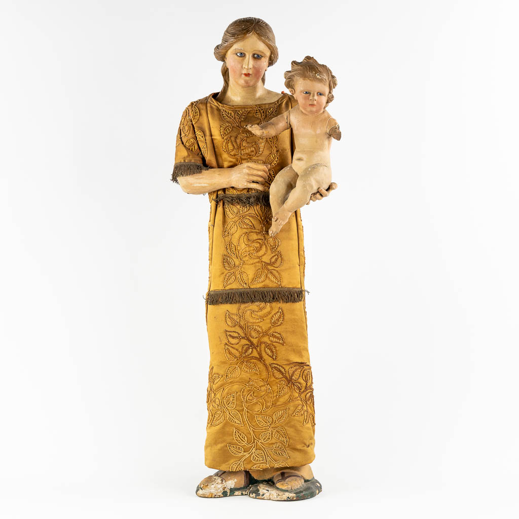 An antique sculptured figurine of a mother with child, wearing an embroidered robe. 19th C. (W:36 x