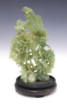 Chinoiserie green jadeite floral carving on a stylised hardwood stand, 23 x 39cm.