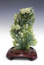 Chinoiserie green jadeite floral carving on a stylised hardwood stand, 21 x 32cm.