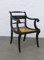 An early 20th century Regency style ebonised & parcel gilt elbow / open armchair, with canework seat