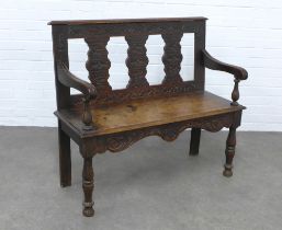 Jacobean style oak bench with carved back and apron, solid seat and open arms, 106 x 95 x 37cm.