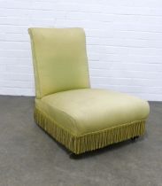 Late 19th century low bedroom chair, upholstered cover with fringing, on mahogany legs with brass