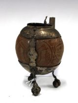 South American white metal mounted and carved gourd, raised on three legs with claw and ball feet,