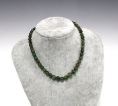 A strand of green jadeite beads with an 18ct gold hand clasp fastening, stamped 18K