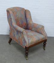 An upholstered armchair on mahogany legs with brass caps and castors, 74 x 103 x 62cm.