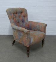 A buttonback upholstered armchair on mahogany legs with brass caps and castors, , 73 x 95 x 65cm.