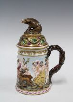 A Capo di Monte tankard decorated in relief with bacchanalian figures, the cover with a boar finial,