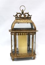 Gilt metal and glass panelled storm lantern with a church candle, 55cm