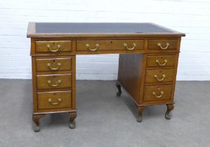An oak desk, with nine drawers and raised on short cabriole legs, 122 x 77 x 65cm.