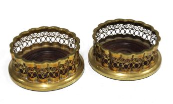 A pair of brass wine bottle coasters with pierced sides and circular wooden bases (2) 16 x 6cm.