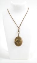 A foliate engraved yellow metal locket on a guard chain, hook clasp stamped 9ct