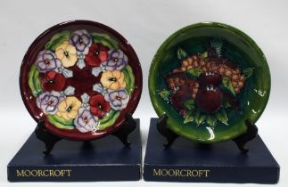 Two Moorcroft Pottery boxed plates to include Pansy and Pomegranates and Finches plate (2)
