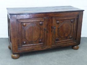 An oak low dresser, rectangular top over a pair of panelled cupboard doors and with fielded panel