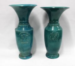 Two raku glazed turquoise baluster vases, each with a flared rim and armorial style crest, taller