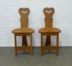 A pair of Arts & Crafts style carved oak hall chairs, stylised tripod design in the manner of