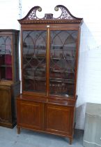 Mahogany bookcase cabinet with swan neck fretwork top and dentil frieze over a pair of astragal