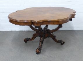 Rosewood center table with an oval serpentine top on a carved supports and legs, 148 x 74 x 107cm.