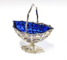 An Edwardian silver sugar basket with pierced design and shaped blue glass liner, swing handle and