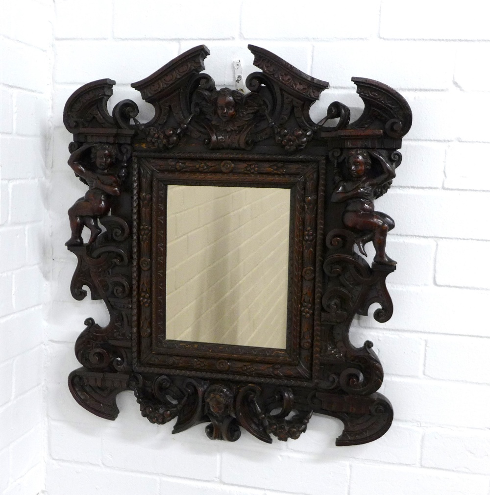 Baroque Revival carved wall mirror, with mask heads, cherubs and broken pediment top, 57 x 65cm.