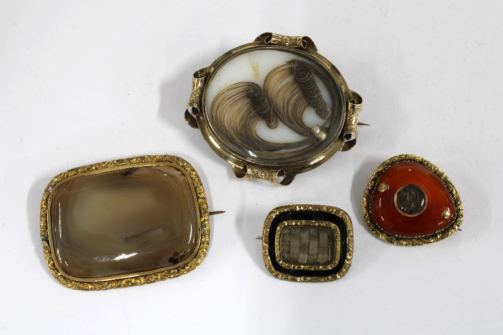 Three 19th century mourning brooches with plaid hair panels and a hardstone brooch in yellow metal