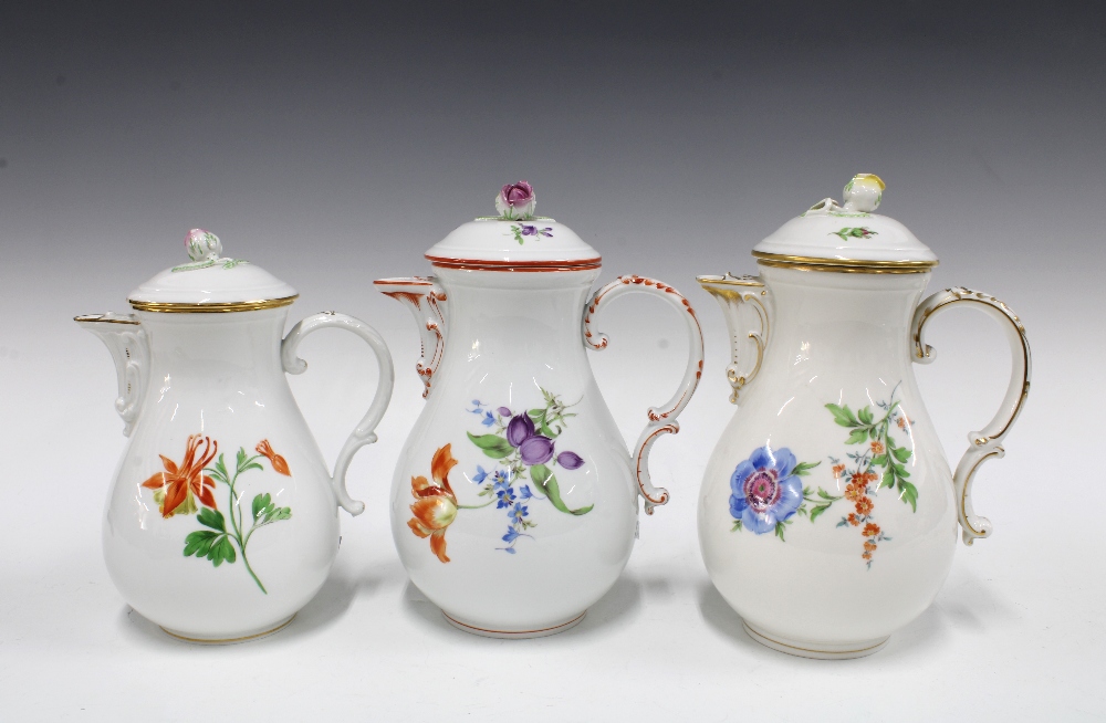 Three Meissen coffee pots of baluster form and painted with flowers, each with a rosebud finial (