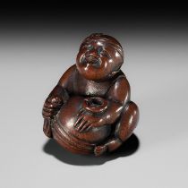 SHOGYOKU: A WOOD NETSUKE OF A BOY POLISHING A MOKUGYO