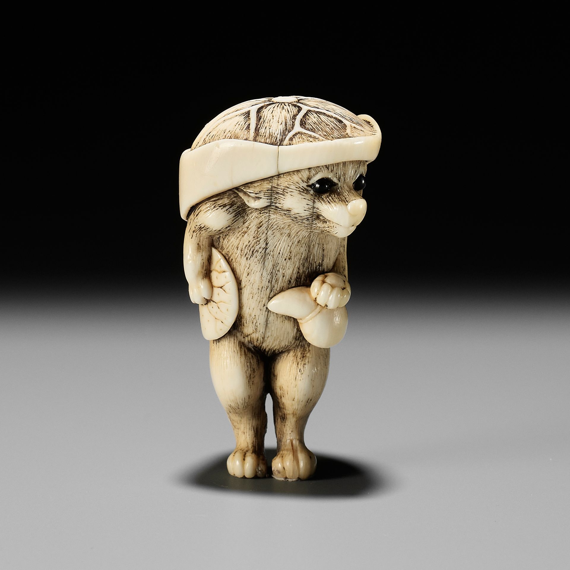 A HUMOROUS OSAKA SCHOOL IVORY NETSUKE OF TANUKI DISGUISED AS A SAKE VENDOR