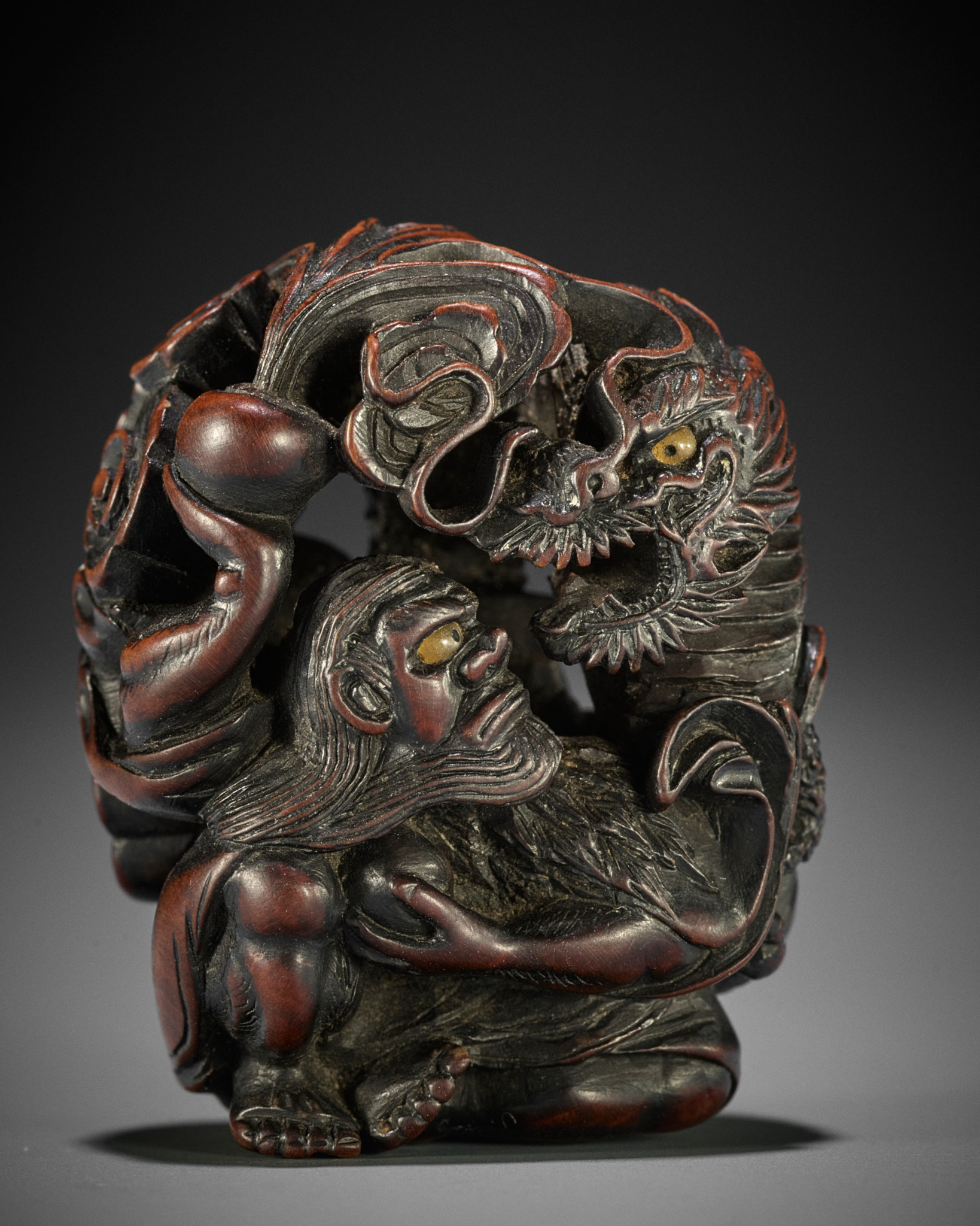 SADAKATA: A SUPERB WOOD NETSUKE OF RAKAN HANDAKA SONJA WITH DRAGON