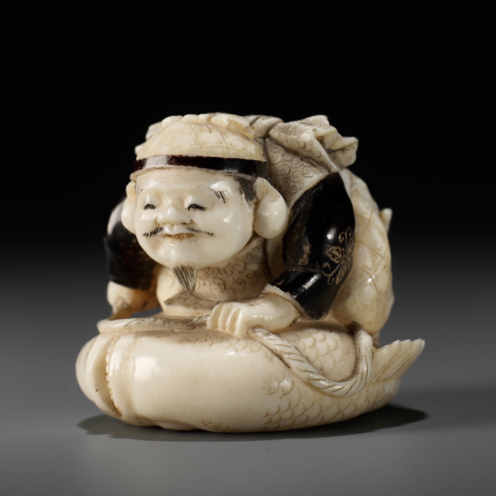 GYOKUMIN: A FINE TOKYO SCHOOL IVORY NETSUKE OF EBISU CATCHING A SEA BREAM