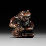 A POWERFUL WOOD NETSUKE OF AN ONI APPLYING MOXA