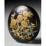 A LACQUERED WOOD MANJU NETSUKE DEPICTING CHRYSANTHEMUMS BY A FENCE