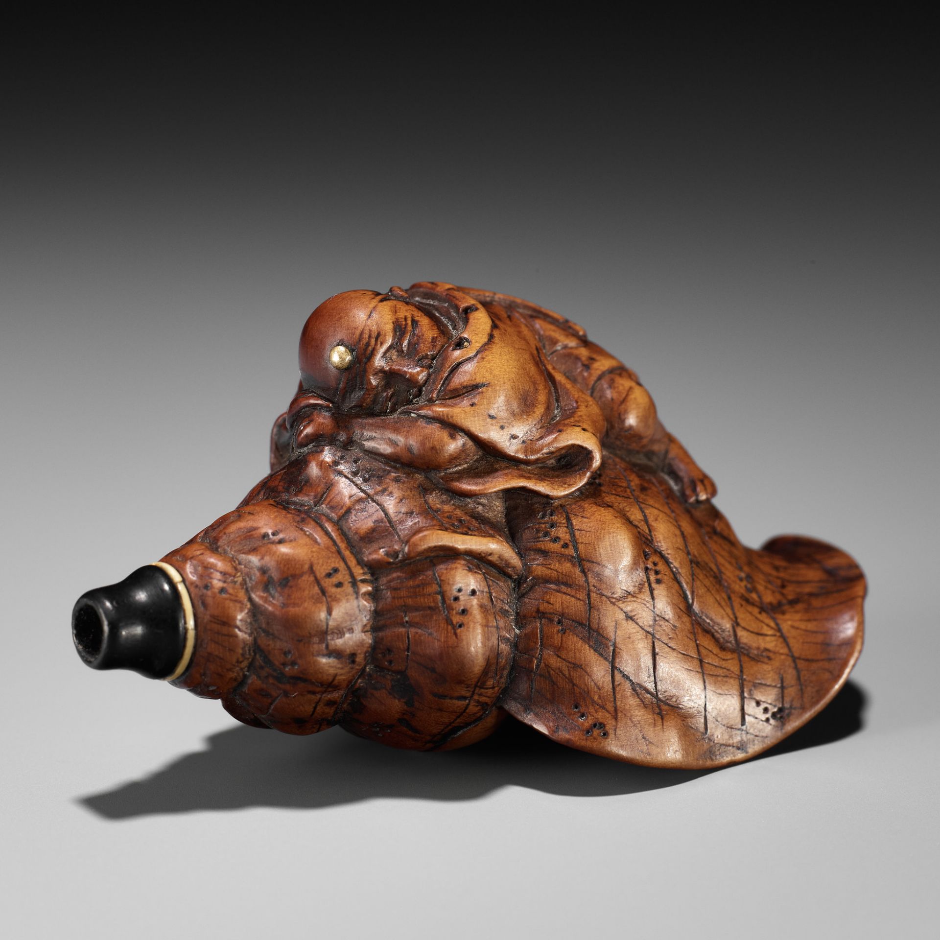 A WOOD NETSUKE OF BENKEI SLEEPING ON A CONCH (HORAGAI)