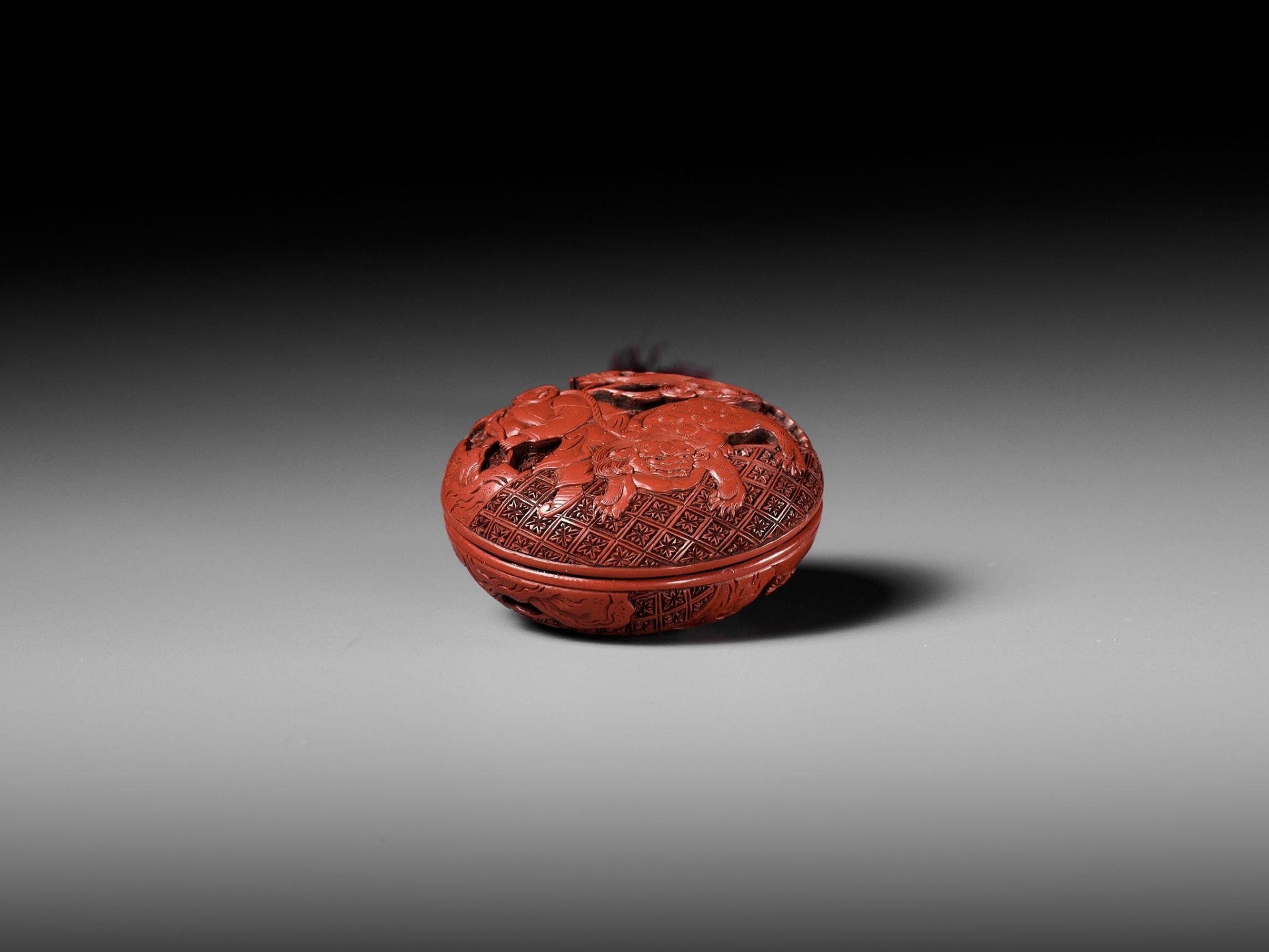 A FINE TSUISHU (CARVED RED LACQUER) MANJU NETSUKE WITH CHINESE LITERATI AND SHISHI - Image 7 of 9