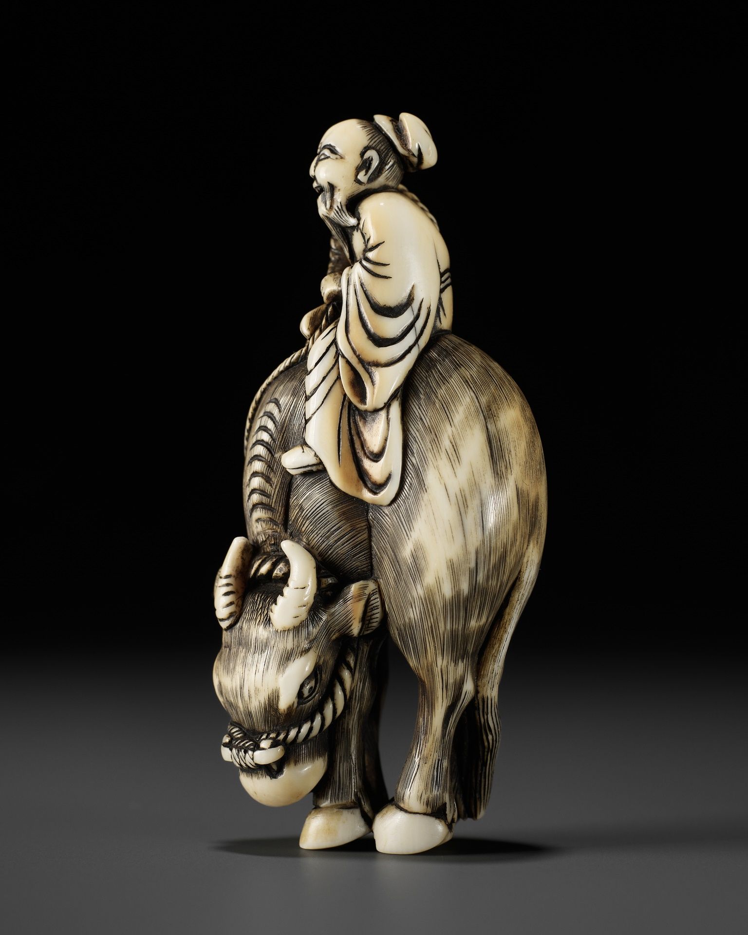 A FINE IVORY NETSUKE OF ROSHI ATOP AN OX